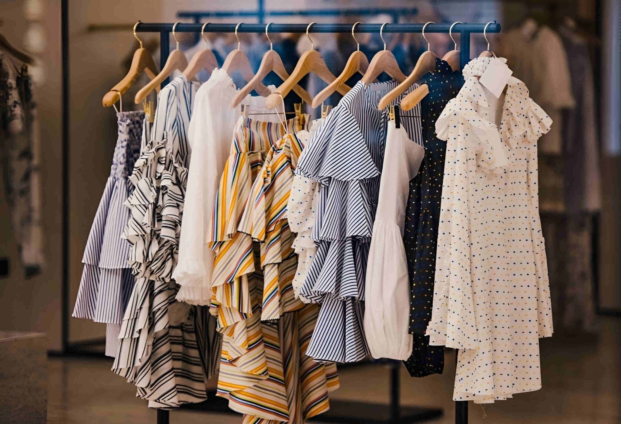 A clothing rack displaying various dresses with patterns and stripes in different colors, including white, yellow, blue, and black.